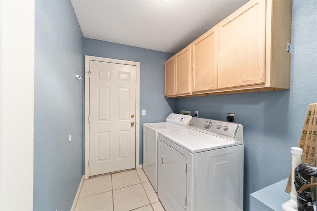 laundry area featuring washer and dryer, light tile patterned floors, and cabinets