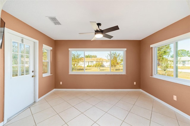 tiled spare room featuring a wealth of natural light and ceiling fan