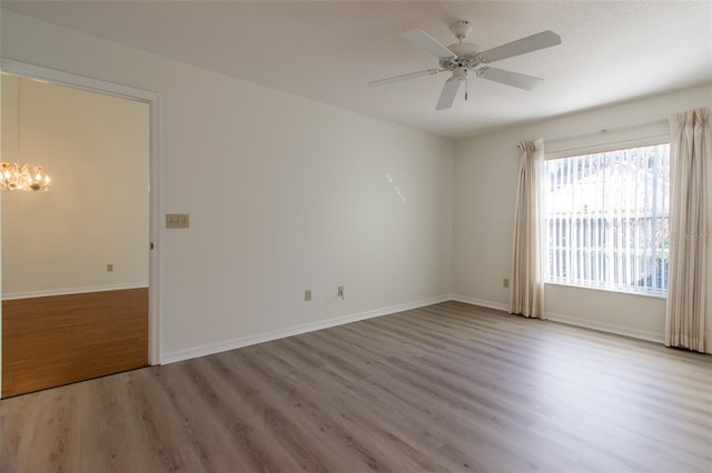 empty room featuring hardwood / wood-style floors and ceiling fan with notable chandelier