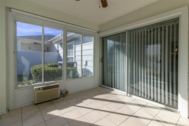 unfurnished sunroom featuring ceiling fan, a healthy amount of sunlight, and a wall mounted AC