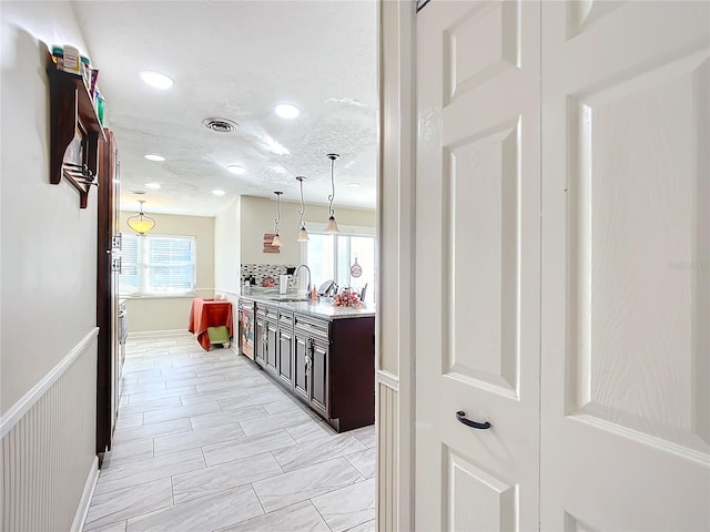 kitchen with hanging light fixtures, dark brown cabinets, plenty of natural light, and sink