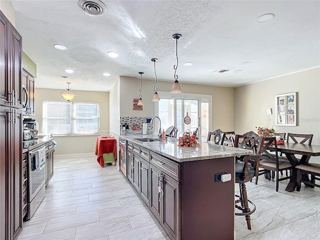 kitchen with a kitchen breakfast bar, decorative light fixtures, and a healthy amount of sunlight