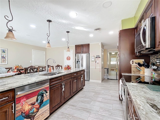 kitchen featuring light stone countertops, a textured ceiling, stainless steel appliances, sink, and hanging light fixtures