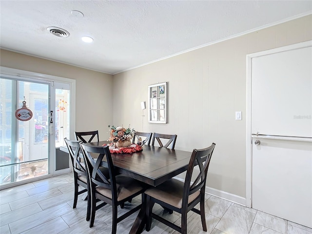 dining area with a textured ceiling, wood walls, and crown molding