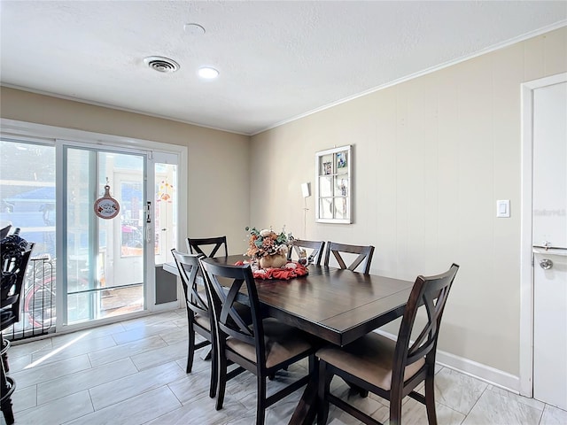 dining area with ornamental molding and a textured ceiling