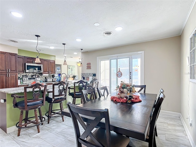 dining room with ornamental molding and a textured ceiling