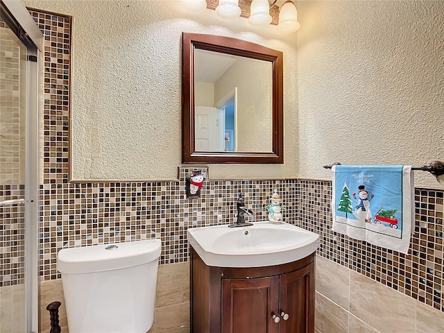 bathroom featuring vanity, tile walls, and toilet