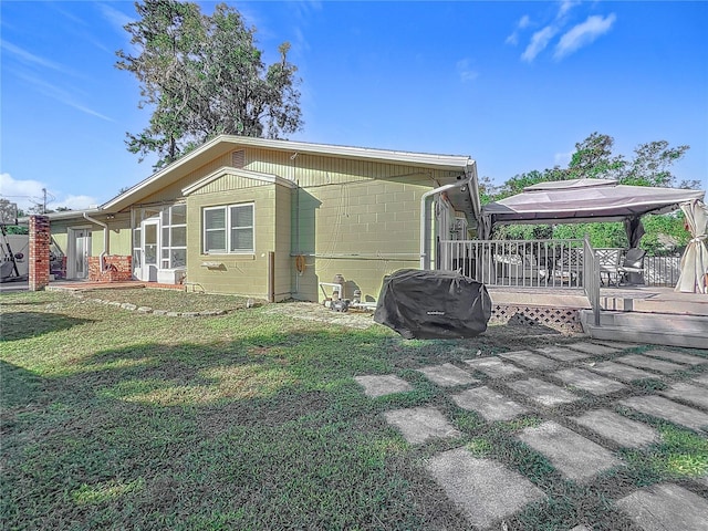 rear view of property featuring a gazebo, a wooden deck, and a yard