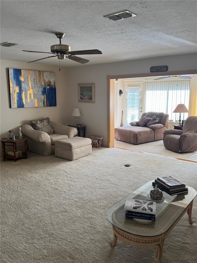 living room with carpet, ceiling fan, and a textured ceiling