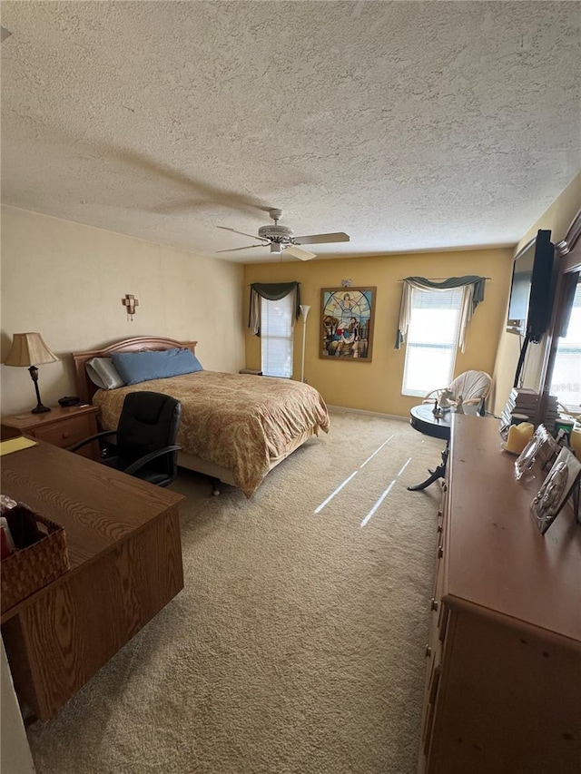 carpeted bedroom featuring ceiling fan and a textured ceiling