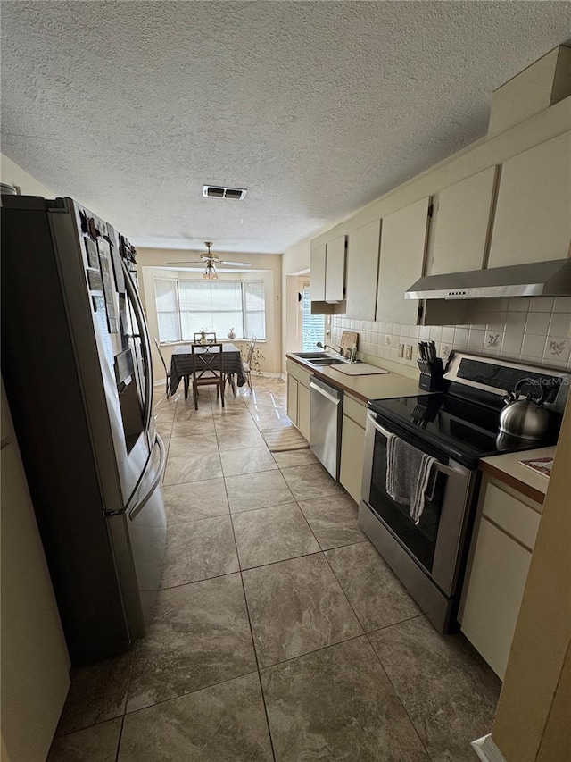 kitchen featuring white cabinets, backsplash, stainless steel appliances, and light tile patterned flooring