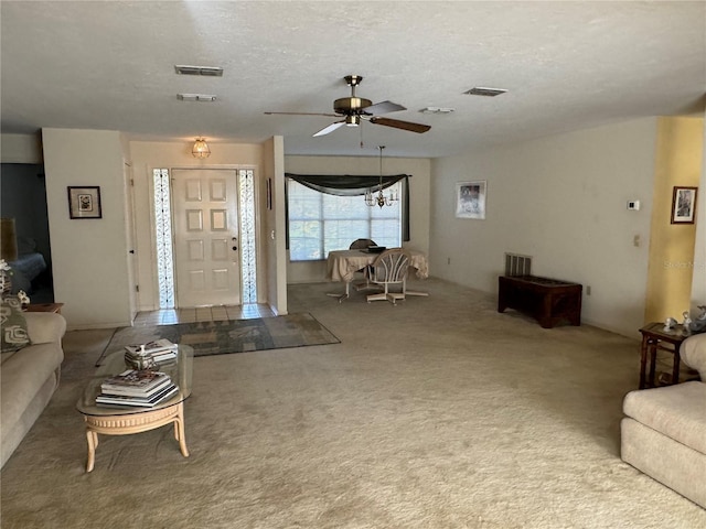 carpeted living room with ceiling fan with notable chandelier and a textured ceiling