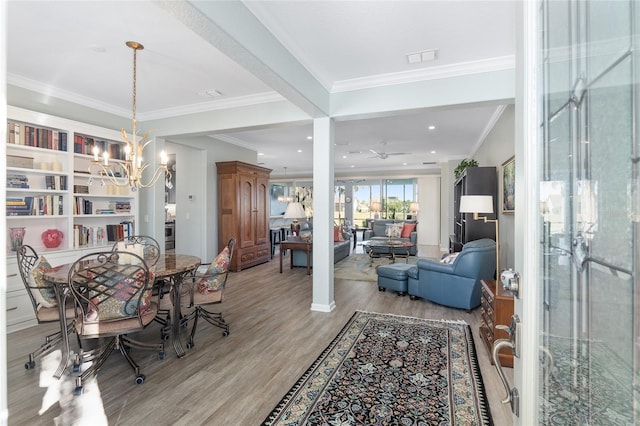 dining room with ceiling fan with notable chandelier, light hardwood / wood-style floors, and ornamental molding