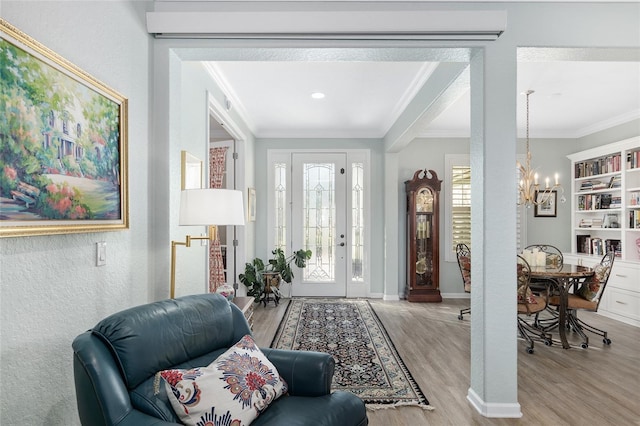 entryway with a chandelier, crown molding, and light hardwood / wood-style floors