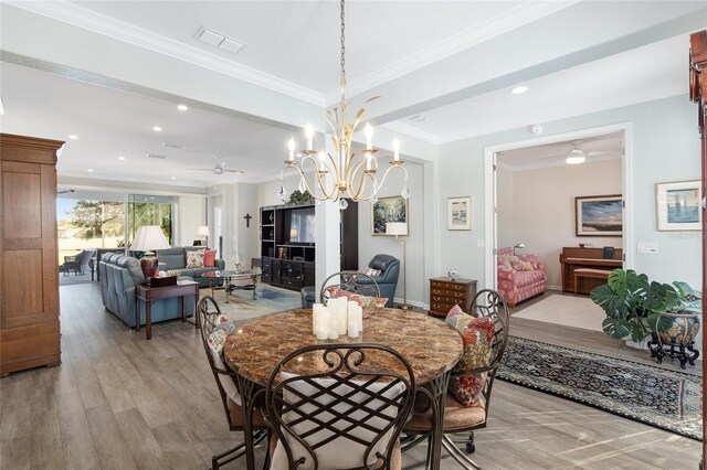 dining area with ceiling fan with notable chandelier, light wood-type flooring, and crown molding