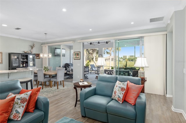 living room featuring ceiling fan with notable chandelier, light hardwood / wood-style flooring, and ornamental molding