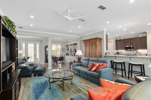 living room with light hardwood / wood-style floors, ceiling fan, and ornamental molding