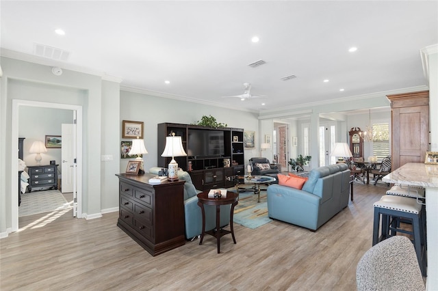 living room featuring ceiling fan with notable chandelier, light hardwood / wood-style floors, and crown molding