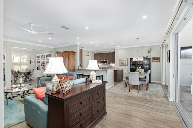 living room with ceiling fan with notable chandelier, light hardwood / wood-style flooring, and crown molding