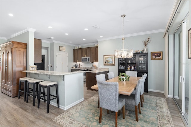 dining room featuring light hardwood / wood-style flooring, a chandelier, and ornamental molding