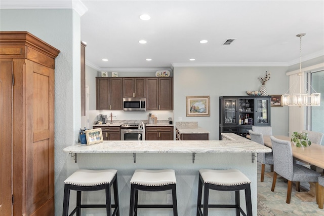 kitchen with kitchen peninsula, appliances with stainless steel finishes, crown molding, and pendant lighting