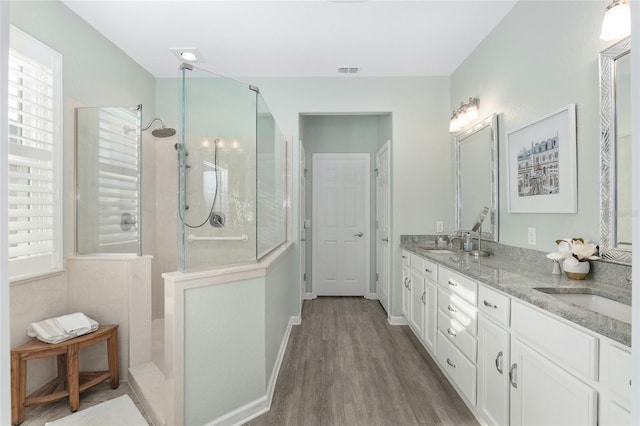 bathroom featuring hardwood / wood-style flooring, vanity, and a tile shower