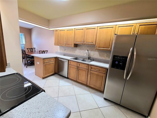 kitchen with kitchen peninsula, tasteful backsplash, stainless steel appliances, sink, and light tile patterned flooring