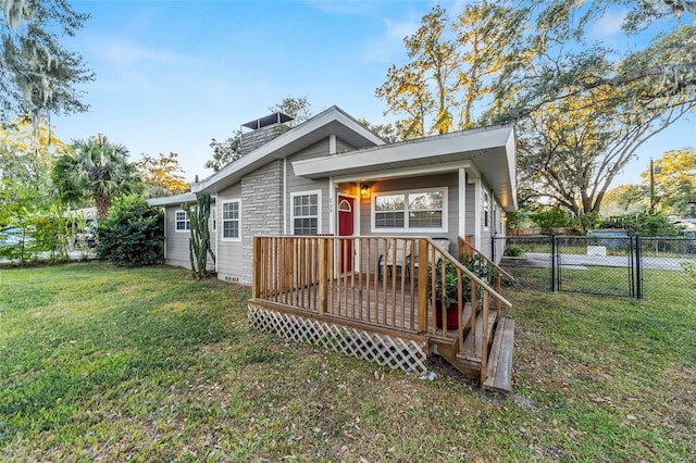 rear view of property featuring a wooden deck and a lawn