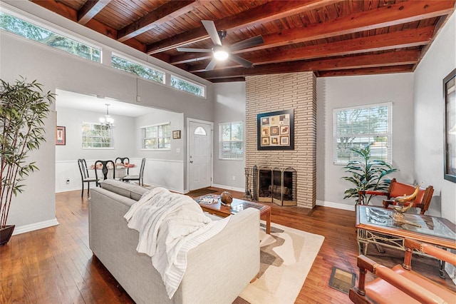 living room with a brick fireplace, wood ceiling, ceiling fan with notable chandelier, hardwood / wood-style floors, and vaulted ceiling with beams