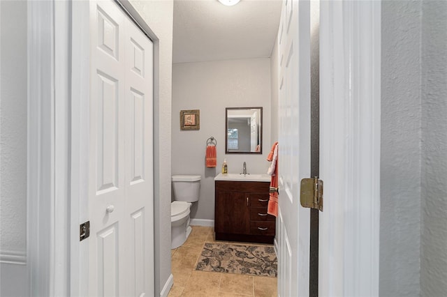 bathroom with tile patterned floors, vanity, a textured ceiling, and toilet