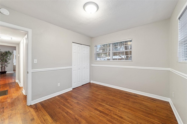 unfurnished bedroom featuring hardwood / wood-style flooring, a textured ceiling, and a closet