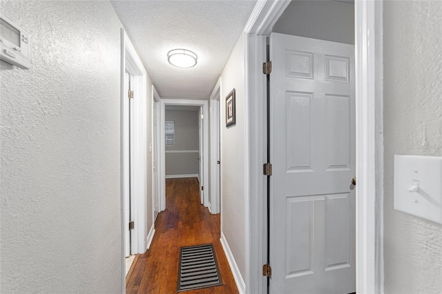 hall featuring a textured ceiling and dark wood-type flooring