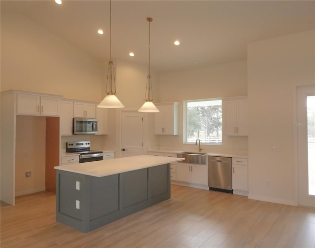 kitchen featuring white cabinetry, a high ceiling, appliances with stainless steel finishes, and a sink