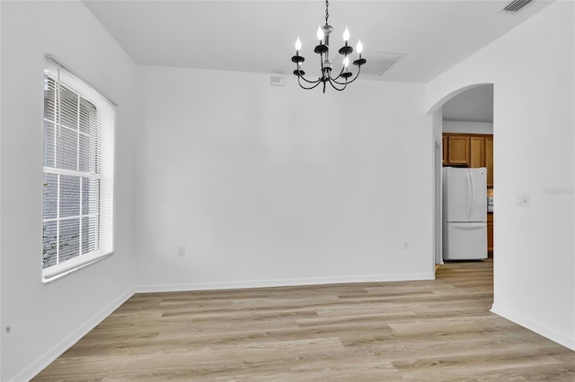 unfurnished dining area featuring a notable chandelier and light hardwood / wood-style floors