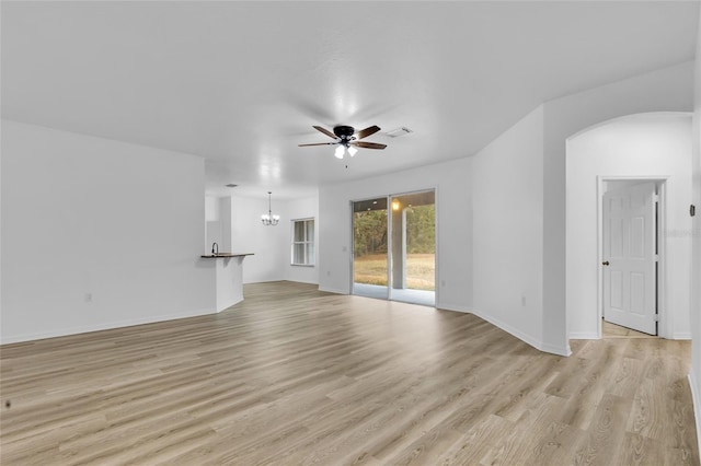 unfurnished living room featuring ceiling fan with notable chandelier and light hardwood / wood-style flooring