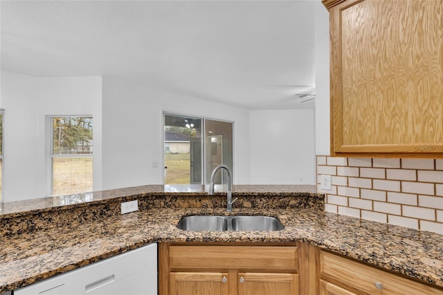 kitchen with dishwasher, dark stone countertops, sink, and a wealth of natural light