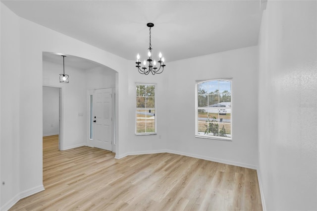 empty room with light hardwood / wood-style floors and a notable chandelier