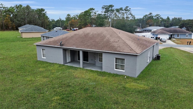 rear view of house with a patio, central AC unit, and a lawn