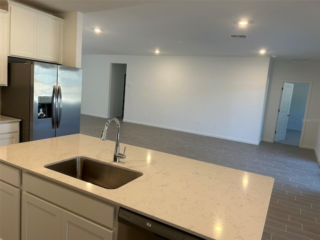 kitchen with light stone countertops, appliances with stainless steel finishes, white cabinets, and sink