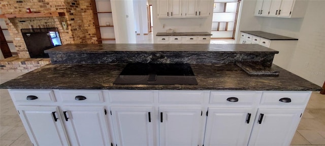 kitchen featuring black electric stovetop, white cabinetry, a kitchen island, and dark stone countertops