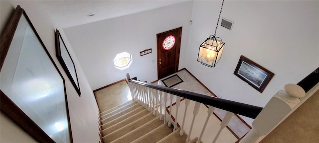 staircase featuring carpet flooring and a notable chandelier