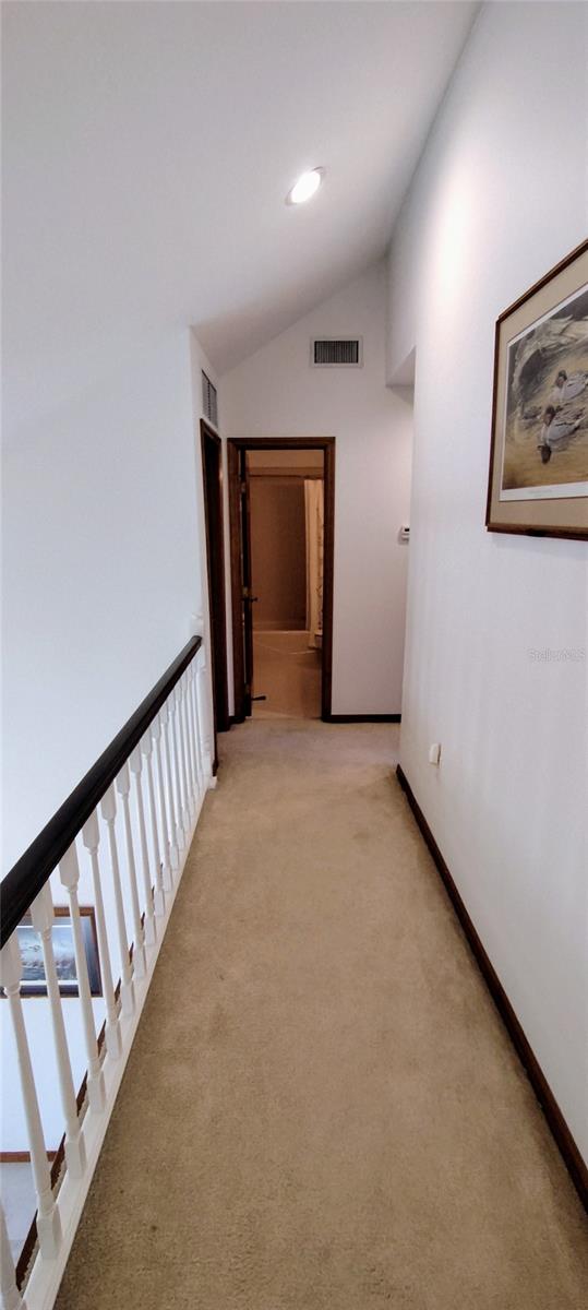 hallway with light carpet and lofted ceiling