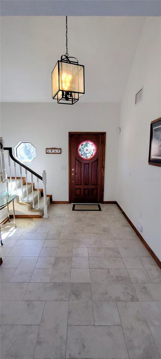 entryway featuring light tile patterned floors, high vaulted ceiling, and a chandelier