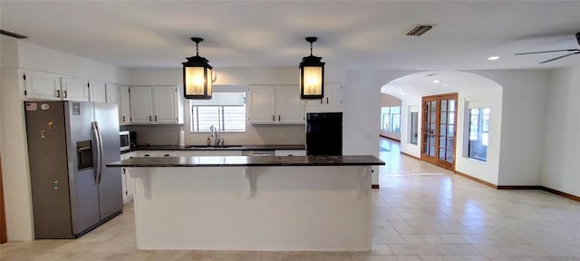 kitchen with white cabinets, stainless steel appliances, a kitchen island, and sink