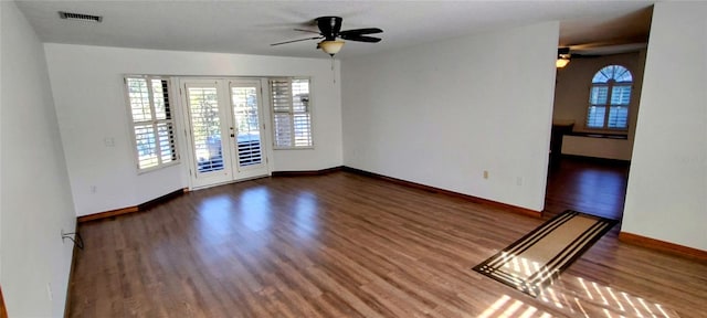 empty room featuring french doors, ceiling fan, and dark wood-type flooring