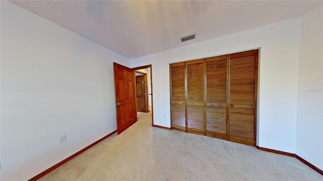 unfurnished bedroom featuring a closet and light colored carpet