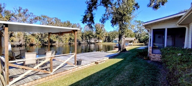 view of dock with a lawn and a water view