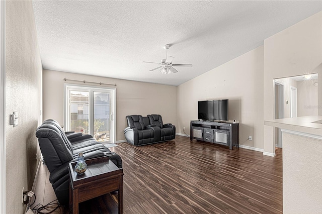 living room with a textured ceiling, ceiling fan, and dark wood-type flooring