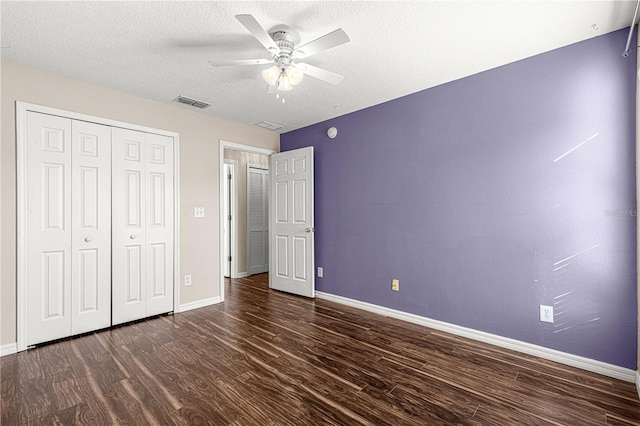 unfurnished bedroom featuring a textured ceiling, ceiling fan, a closet, and dark hardwood / wood-style floors