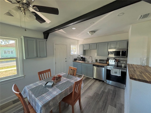 dining room featuring dark hardwood / wood-style floors, beam ceiling, sink, and a wealth of natural light